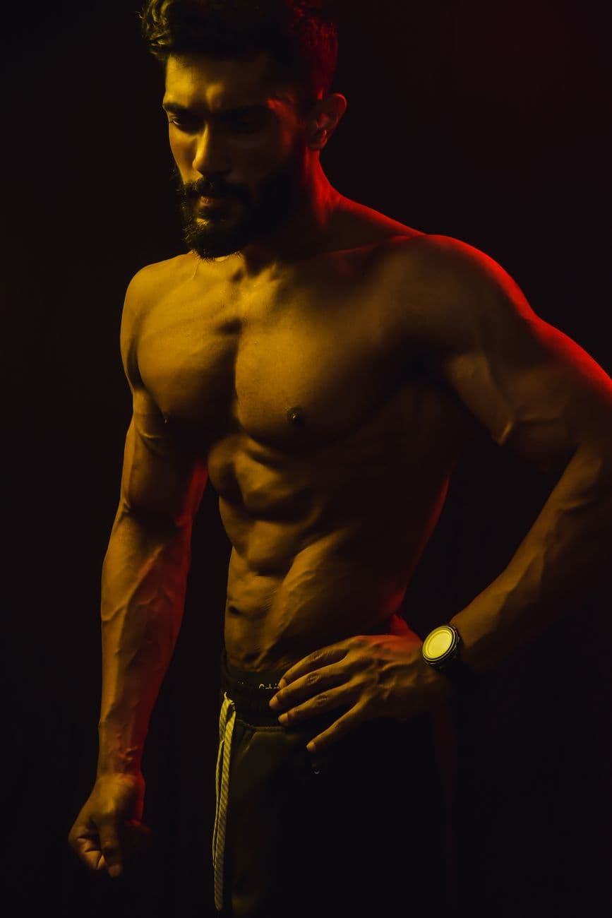 Muscular athlete under dramatic red and gold lighting